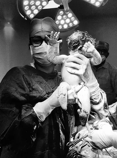 Dr. Deepika Rawat in the operation theatre holding a newborn moments after delivery