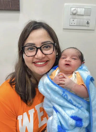 Dr. Deepika Rawat smiling with a newborn baby